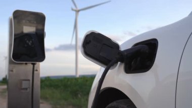 Çevreyi korumak için rüzgar türbininden yeşil ve yenilenebilir enerjiyle çalışan şarj istasyonunda şarj edilen gelişmiş gelecek enerji altyapısı konsepti.