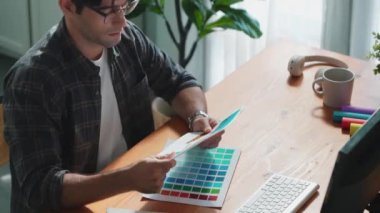 Toplantıda profesyonel tasarımcı yazma ve logo grafiği tasarlama. Renkli paletler üzerinde çalışan iş adamlarının yakınlaşması ve masaya kağıt ve ekipman ile yapışkan notlar yazmak. Sempozyum.