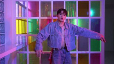 Kameraya bakarken kollarını esneten seksi kıyafetli Asyalı dansçı. Profesyonel sanatçı gece kulübünde renkli neon ışıkları canlı bir şekilde dururken serbest stil dansı yapıyor. Mutluluk.