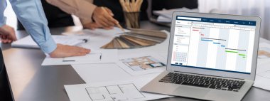 İç mimar tasarımcı grubu, daha kesin tasarım için planlar ve dizüstü bilgisayar ekran mimari yazılımı üzerinde birlikte tartışıyorlar. Modern ev tasarımı ve yenileme. İçgörü