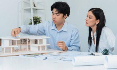 Kooperatif mühendis ekibinin portresi ev modelini ölçmek için cetvel ve mimari ekipmanlar kullanarak birlikte çalışıyor. Yaratıcı iş tasarımı ve takım çalışması konsepti. Tertemiz...