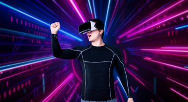 VR gözlüklü akıllı erkek oyuncu oyunu parlak neon ışıkla kazandığı için kutlama yapıyor. Heyecanlı oyuncu, artırılmış gerçeklik teknolojisini kullanarak oyundaki zaferini kutluyor. Yaratıcılık.