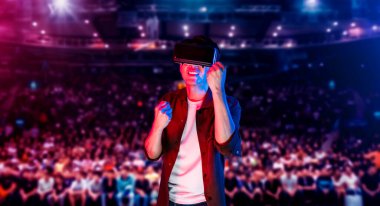 Asyalı bir adam VR gözlük ve günlük giysiler takıyor ve kalabalıkla çevrili, tezahürat yapıyor ve arenada oturuyor. Oyuncu, artırılmış gerçeklik teknolojisini kullanarak bilgisayar oyununda kazanmayı kutluyor. Yaratıcılık.