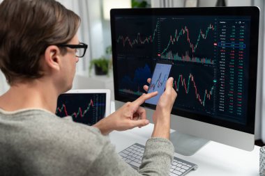 Akıllı borsa yatırımcıları ekranda akıllı telefon ile piyasa borsasını işaret ederek dizüstü bilgisayarın yanı sıra en yüksek dinamik yatırım oranını göstererek, modern işyerindeki veri planlamasına odaklanıyorlar. Bireysel.