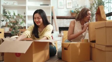 Çekici bir oda arkadaşı oturma odasında paket paketlerken pakette konum yazıyor. Mutlu satıcı birlikte çalışıyor ve teslimat paketini hazırlıyor. Girişimci kargo kutusu paketliyor. Myrmidon.