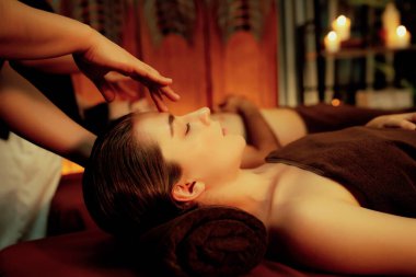Stres önleyici kafa masajının keyfini çıkaran ve lüks otel veya otellerde sıcak mum ışığında cilt bakımını şımartan bir çift müşteri. Sessiz.