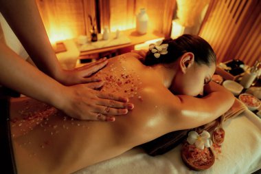 Lüks spa salonlarında sıcak mum ışığında cilt bakımı yaptıran kadın müşteri. Sağlık Spa vücut fırçasında tuz temizleme güzellik tedavisi. Sessiz.