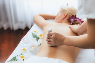 Sıcak bitkisel top spa masaj vücut tedavisi, masör kadın vücuduna nazikçe şifalı bitki torbası bastırıyor. Aromaterapi dinlenme sükuneti ve sükuneti kaplıca salonundaki atmosferi aydınlatıyor. Sessiz.