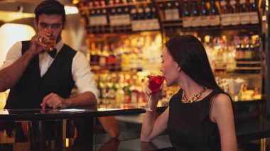 Barmen çiçekle süslenmiş karışık votka servisi yapıyor. Güzel bir konukla tezahürat yapıyor. Lüks tezgah barında oturuyor. Vinosity.