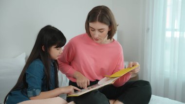 Beyaz bir anne, tatlı kızının dinlediği hikayeleri okuyor. Asyalı kız yatmadan önce hikâyeyi anlatırken işaret etti. Birlikte vakit geçirirken mutlu bir aile yatakta oturuyor. Pedagoji.