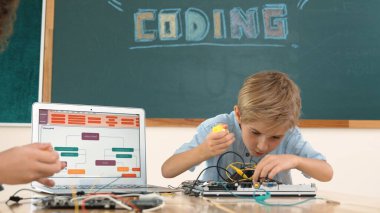 Kafkas akıllı çocuk kök teknoloji dersinde tornavida kullanarak ana tahtayı tamir ederken aynı zamanda gülümseyen öğrenci de dizüstü bilgisayar ekranı kodlu elektronik makineyi incelemek için birlikte çalışıyor. Pedagoji.