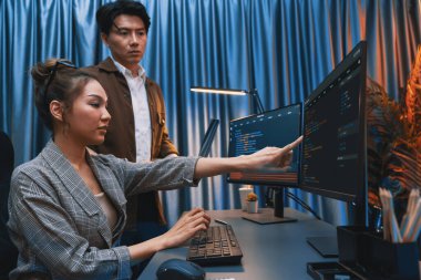 Bilgi teknolojisi geliştiricileri modern ofisteki neon ışık odasında verileri çevrimiçi olarak çalıştıran akıllı web sitesi geliştirme kodlayıcı sistemine işaret ediyorlar. İnfobahn.