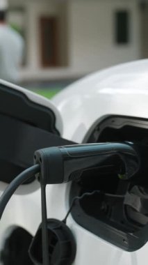 İlerici ebeveynler kızlarını okuldan alırken elektrikli araba ve yenilenebilir enerji kavramını kullandılar, evdeki EV otomobil için şarj istasyonu. Alternatif eko taşımacılığı.