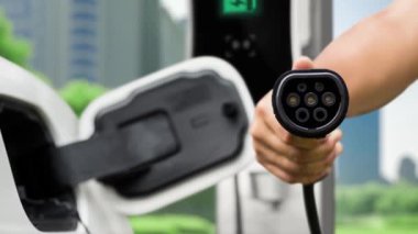 Kameranın önüne odaklanmış EV şarj cihazı fütüristik akıllı dijital EV batarya durum hologramını gösteriyor. EV araba şarjı sürdürülebilir güç için alternatif enerji kullanıyor. İnceleyin