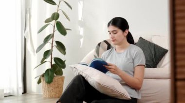 Kanepede oturan bir kadın ders kitabı okuyarak sosyal ve mesleki teknoloji bilgisini artırır ya da akıllı bir anne olmak için çocuk yetiştirir. Hayat boyu öğrenme konsepti. Uyumsuzluk.