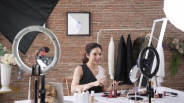 Kadın nüfuzlu kişi canlı yayın yapan video görüntülerini sosyal medya ya da blog üzerinden gözden geçiriyor. Kozmetik stüdyosu ışıklandırmalı mutlu genç kız çevrimiçi pazarlama oturumu yayını için..