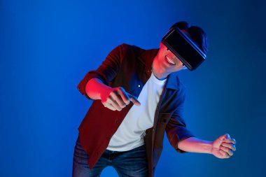 VR kullanan zeki bir oyuncu araba yarışlarında araba sürerken yeni dünyaya dönüyor mavi neon ışıklı duvar bağlantılı fütüristik teknoloji sanal gerçeklik meta 'sını izole ediyor. Entrika.