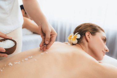 Lüks spa salonlarında sıcak mum ışığında cilt bakımı gören mutlu çift müşterisi. Sağlık kaplıcasında güzellik tedavisiyle tuz temizliği. Sessiz.
