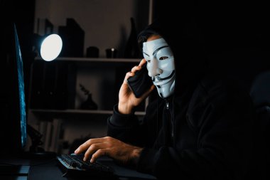 Beyaz gülümseyen isimsiz suçlu maskesi kurbana sesleniyor, kişisel bilgileri hacklemeye ikna ediyor, veri sunucu sistemindeki bilgisayar korsanlarının kullandığı şifreleme programını paylaşıyor. Tahmin et..