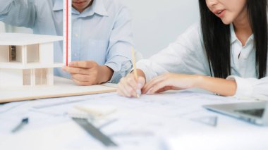 Profesyonel mühendis ev modelini tartartarken, yetenekli tasarımcı da planına yazar. Birlikte çalışmak, işbirliği, işbirliği. Yaratıcı tasarım ve takım çalışması konsepti. - Yakın çekim. Tertemiz.