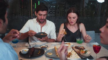 Grup arkadaşı ya da çift, ızgarada ve ana yemek masasında yemek yerken akıllı telefonla konuşuyor. Lüks restoranda etkileyici bir dostluk ortamında tanışma teması. Vinosity.