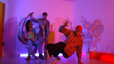 Stüdyoda gündelik kıyafetleri olan çok kültürlü bir arkadaş tezahürat yaparken mutlu hipster break dansları. Profesyonel sokak dansçısı hip hop ritmi ya da neon veya kurşun ışıkla kafiyeli bir şarkı söyler. Mutluluk.
