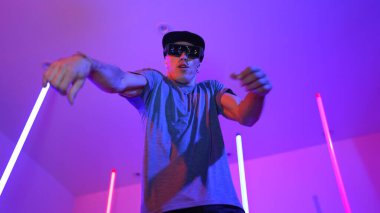 Beyaz dansçının gösterişli gözlükler taktığı ve break dans yaptığı alçak açılı kamera. Çekici adam kendinden emin bir şekilde kameraya bakarken enerjik bir performans ve hareket gösterdi. Mutluluk.