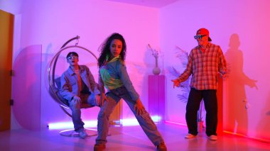 Çekici mutlu dansçı kameraya bakarken zeki kadın neon ışıkla kafiyeli hareket ediyor. Profesyonel İspanyol şarkıcı çeşitli arkadaşlarıyla renkli kıyafetler giyerken break dans yapıyor. Mutluluk.