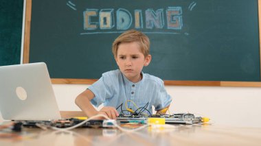 Kameraya karatahta ile bakarken elektronik tahtada çalışan zeki bir öğrenci. Çocuk, kodlama mühendisliği ve yapay zeka kullanarak programlama sistemine hazırlanırken ana tahtayı tamir ediyor. Pedagoji.