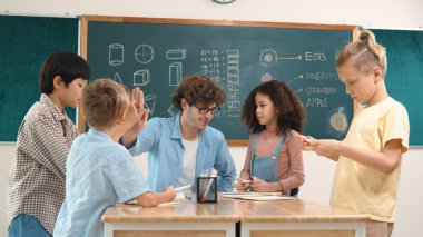 Zeki öğretmen, çeşitli çocuklar sınıf çalışması yapmak için birlikte çalışırken farklı çocukların zihin haritası çizdiği fikri açıklıyor. Çekici eğitmen öğretmek ve çalışmak hakkında konuşmak. Pedagoji.