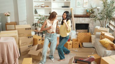 Taşınırken oturma odasında mutlu lezbiyen aşıklar dans ediyor. Birkaç arkadaş müzik eşliğinde salonda karton kutularla dans ederek serbest dans ediyorlar. Yeniden yerleştirme. Myrmidon.