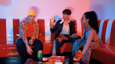 Takım çalışmalarını kutlamak için neon lambalı çok kültürlü bir arkadaş bardak tokuşturuyor. Renkli meyve suyu ve tokuşturarak şık modaya sahip profesyonel çeşitli insanlar. Mutluluk.