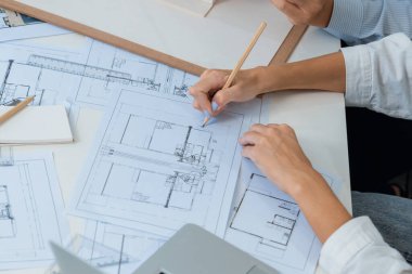 Asyalı kooperatif iş arkadaşı ev modelini ev modeliyle ve bina planıyla birlikte masaya koyarken, profesyonel güzel mimarın el yapımı taslaklarının en üst görüntüsü. Tertemiz..