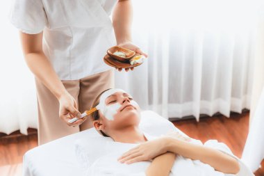 Kaplıca salonunun sakin atmosferi, kadın müşteri modern gün ışığında lüks yüz kremi masajıyla kendini yenileme zevkine kapılıyor. Yüz bakımı ve güzellik konsepti. Sessiz.