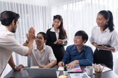 Çeşitli ofis çalışanlarından oluşan bir grup, stratejik iş pazarlama planlaması konusunda anlaşma yaptıktan sonra beşlik çaktı. Takım çalışması ve olumlu tutum verimli ve destekleyici bir iş yeri yaratır. Tedbirli