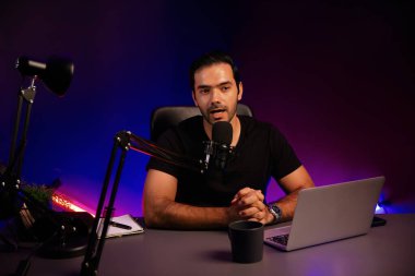 Yayıncı, fanclub dinleyicisiyle mikrofon kullanarak konuşuyor. Mor neon ışıklı modern stüdyoda yaratıcı olumlu düşünce konseptiyle canlı yayında finansal sorunları tartışıyor. Tahmin et..