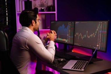 Akıllı tüccar işadamı, karanlık oda gecesinde neon ışıklı ofisteki arama pazarında yüksek kârla ekranda bilgisayar ve bilgisayar üzerinde dinamik borsa yatırımları üzerinde yoğunlaşıyor. Tahmin et..