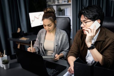 Satış müdürünün dizüstü bilgisayarında çalışan ciddi bir yüz sekreterli müşteriyi arıyor ve modern ofiste gece geç saatlerde evrak işleri ile ilgili notlar yazıyor. Aşırı çalışan problem projesi kavramı. İnfobahn.