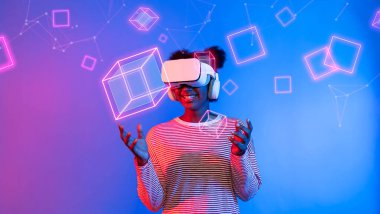 VR gözlüklü Afrikalı kız mavi ve pembe arka planda duruyor ve yüzen geometrik şekle bakıyor. Heyecanlı insan görsel gerçeklik dünyasına giriyor. Teknoloji yeniliği. Yaratıcılık.