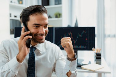 Gülümseyen tüccar işadamının yumruğunu kaldırması, borsa yatırım analizi ekranına karşı telefonla araması ve merkez ofise yüksek kârlı bir finans teknolojisi piyasası yatırması konusunda başarılı oldu. Tahmin et..