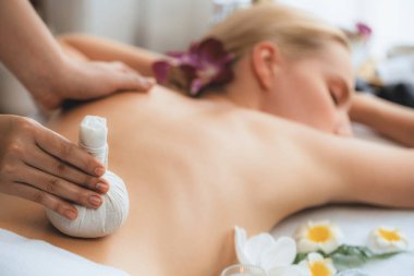Sıcak bitkisel top spa masaj vücut tedavisi, masör kadın vücuduna nazikçe şifalı bitki torbası bastırıyor. Aromaterapi dinlenme sükuneti ve sükuneti kaplıca salonundaki atmosferi aydınlatıyor. Sessiz.