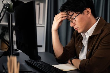 Stresli yüzü olan akıllı işadamı, gece geç saatlerde ofiste iş planı raporu hazırlamak için bilgisayar üzerinde çalışıyor ve yeni bir şirket kurma projesi için araç pazarı planlaması üzerinde çalışıyor. İnfobahn.