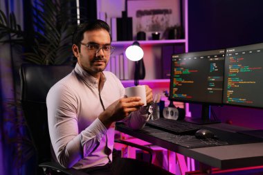 Bilgisayar ekranındaki yazılım geliştirme kodlarında kahve fincanı tutan akıllı bilişim geliştiricisi profili. Program güncellemesi internet sitesi verilerini neon ışığı siber ofisinde sunuyor. Tahmin et..