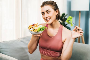 Spor giyimli sağlıklı ve vejetaryen bir kadın bir kase meyve ve sebzeyle. Sağlıklı beslenme ve spor için vejetaryen yaşam tarzı ev konseptinde vücut fiziği.