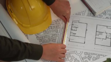 Mimari belge, ölçüm aracı ve ahşap blokların modern ofiste etrafa saçıldığı bir masa üzerinde yapı inşaatı ile ilgili mimar ve güvenlik mühendisi tartışması. Tanımlama.