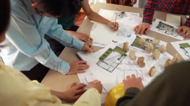 Mimari belge, ölçüm aracı ve ahşap blokların modern ofiste etrafa saçıldığı bir masa üzerinde yapı inşaatı ile ilgili mimar ve güvenlik mühendisi tartışması. Tanımlama.