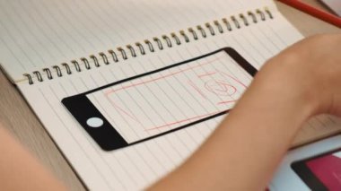 Mobil uygulama için kullanıcı arayüzü prototipi ya da masadaki program modeliyle birlikte web sitesi planlaması yapan bir şirket çalışanı. UX UI tasarımcısı kullanıcı dostu arayüz planını dikkate alır. Sinerjik