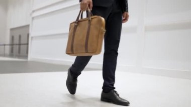 Profesyonel iş adamının bacağını tutarken yakın plan fotoğrafı. Proje yöneticisinin bacağa odaklanmış görüntüsü. Seyahat, taşınma, yolculuk, yürüyüş, yeni bir pozisyon alma, iş değiştirme. Sevinçli..