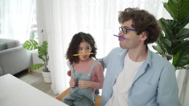 Komik beyaz bir baba ve Amerikalı bir çocuk dudak ve burun arasına kalem koyarken komik bir yüz ifadesi takınıyorlar. Birlikte mühendislik komut yazma ve masadaki dizüstü bilgisayarda yapay zeka üretme üzerine sevimli bir aile çalışması. Pedagoji.