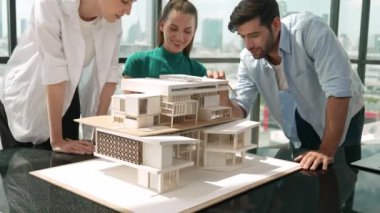 Beyaz proje yöneticisi dizüstü bilgisayar analiz verilerini kullanırken, mimar mühendis ekibi ev modeli inşaatını analiz etmek için birlikte çalışıyor. Bir grup tasarımcı ev tasarımı hakkında konuşuyor. İzleme